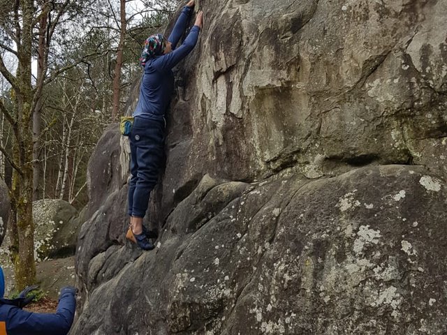 Grimpeur en action sur un grand bloc, guidé depuis le sommet, Fontainebleau janvier 2025