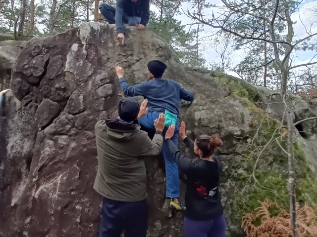 Groupe qui parade un grimpeur sur un bloc en forêt de Fontainebleau, janvier 2026